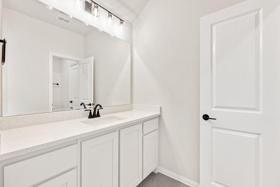 Bathroom vanity with white cabinets, quartz countertop, single sink, and large mirror with overhead lighting. Bathroom vanity with white cabinets, quartz countertop, single sink, and large mirror with overhead lighting.