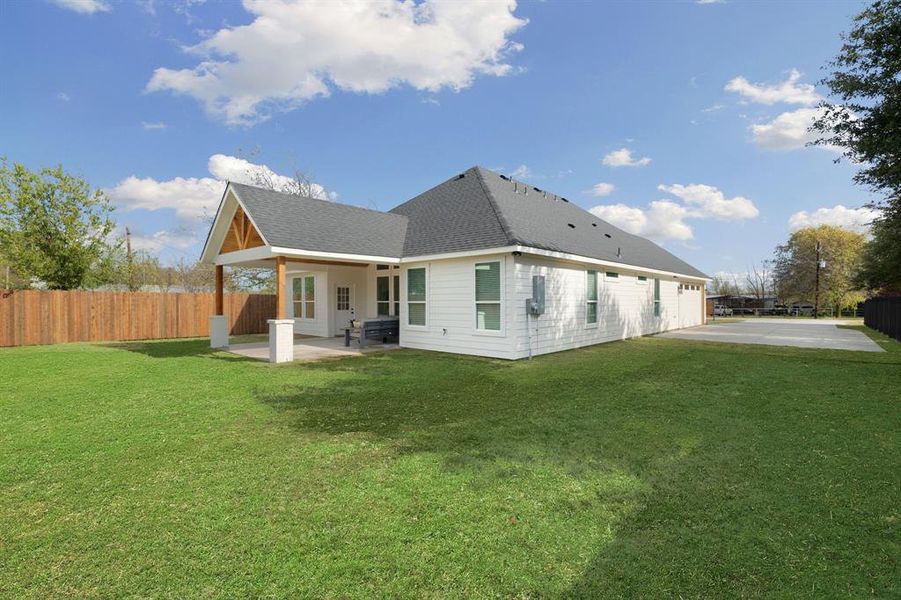 Back of house featuring a patio area, roof with shingles, a fenced backyard, a garage, and driveway Back of house featuring a patio area, roof with shingles, a fenced backyard, a garage, and driveway