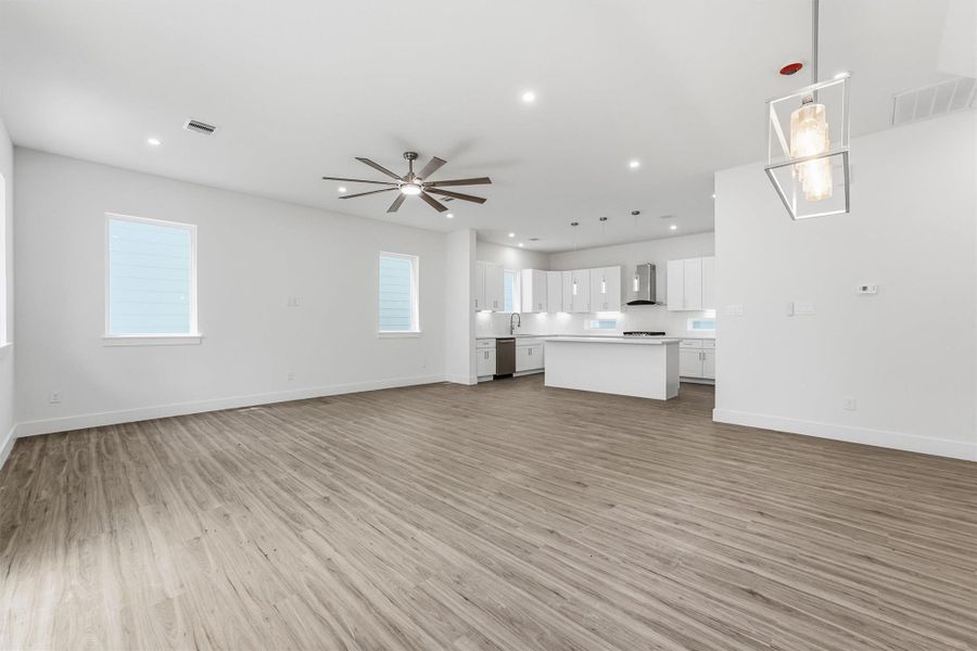 Open-concept living area with wood-look flooring and seamless flow into the kitchen and dining area.