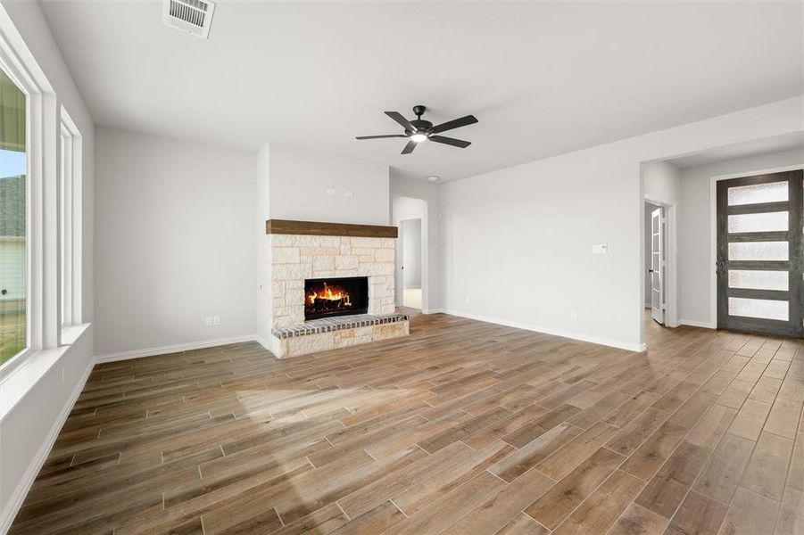 Unfurnished living room with a stone fireplace, ceiling fan, and wood finish floors Unfurnished living room with a stone fireplace, ceiling fan, and wood finish floors