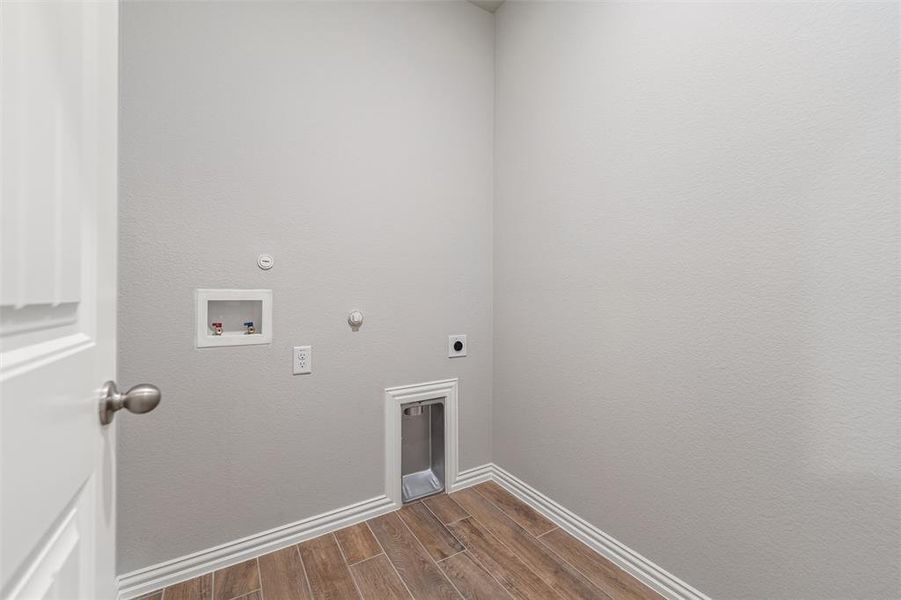Laundry area featuring wood tiled floors, hookup for a gas dryer, electric dryer hookup, and hookup for a washing machine Laundry area featuring wood tiled floors, hookup for a gas dryer, electric dryer hookup, and hookup for a washing machine
