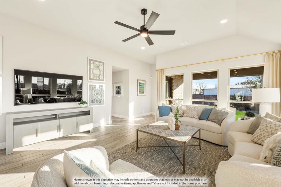 Bright living room with ceiling fan, large TV, neutral sofas, and wood-look floors with backyard windows. Bright living room with ceiling fan, large TV, neutral sofas, and wood-look floors with backyard windows.