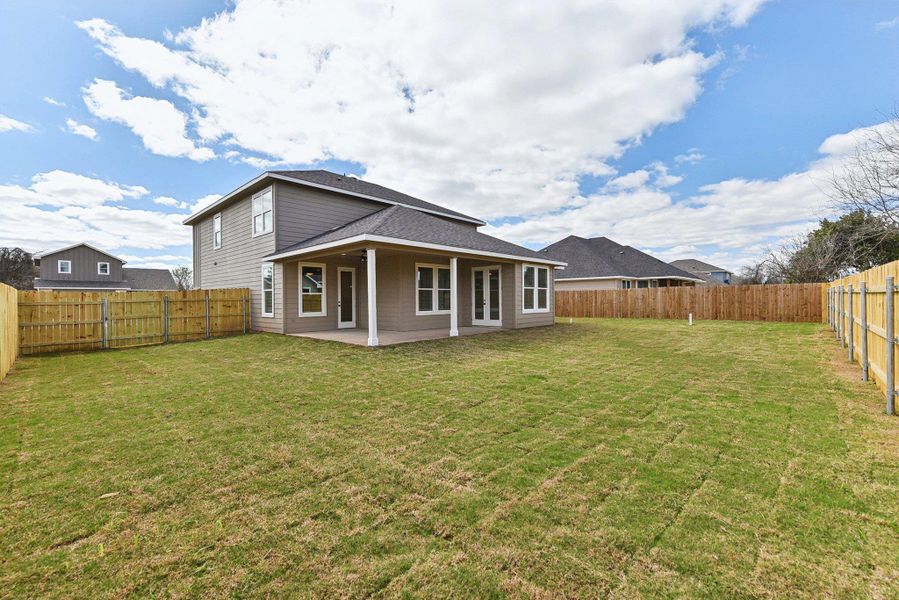 Rear view of house with a lawn, a fenced backyard, and a patio area