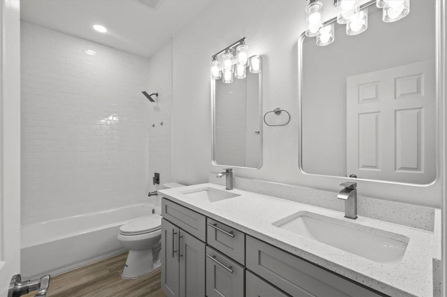 Bathroom featuring shower / tub combination, toilet, wood finished floors, and a sink