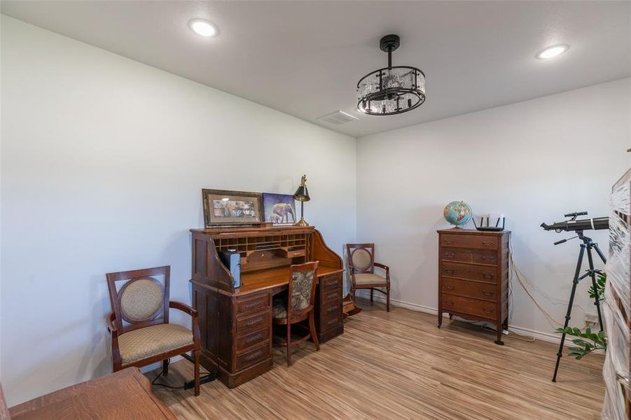Versatile room featuring wood-finish flooring, recessed lighting, and a contemporary semi-flush mount ceiling fixture Versatile room featuring wood-finish flooring, recessed lighting, and a contemporary semi-flush mount ceiling fixture