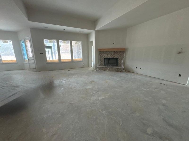 Unfurnished living room featuring a stone fireplace and concrete flooring