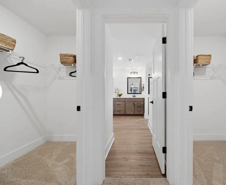 Dual walk-in closets flank a hallway leading to a Dual walk-in closets flank a hallway leading to a