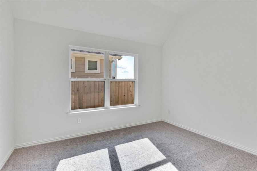 Carpeted spare room featuring vaulted ceiling and baseboards Carpeted spare room featuring vaulted ceiling and baseboards