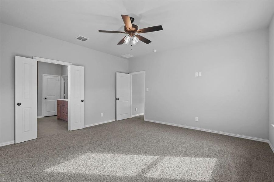 Unfurnished bedroom with light carpet, ensuite bath, and ceiling fan