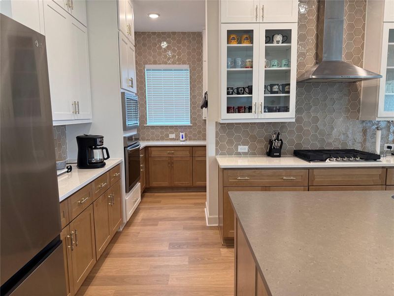 Modern kitchen with sleek stainless steel appliances, elegant quartz countertops, and stylish honeycomb tile backsplash to ceiling!