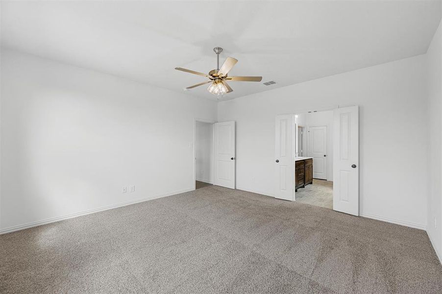 Unfurnished bedroom featuring light carpet, connected bathroom, and ceiling fan