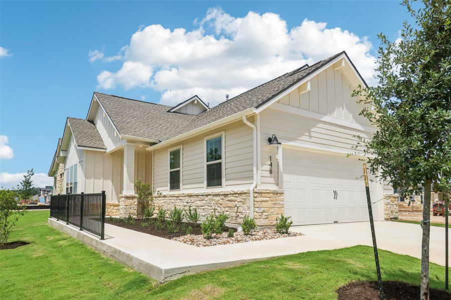 View of front of home featuring board and batten siding, roof with shingles, stone siding, and concrete driveway