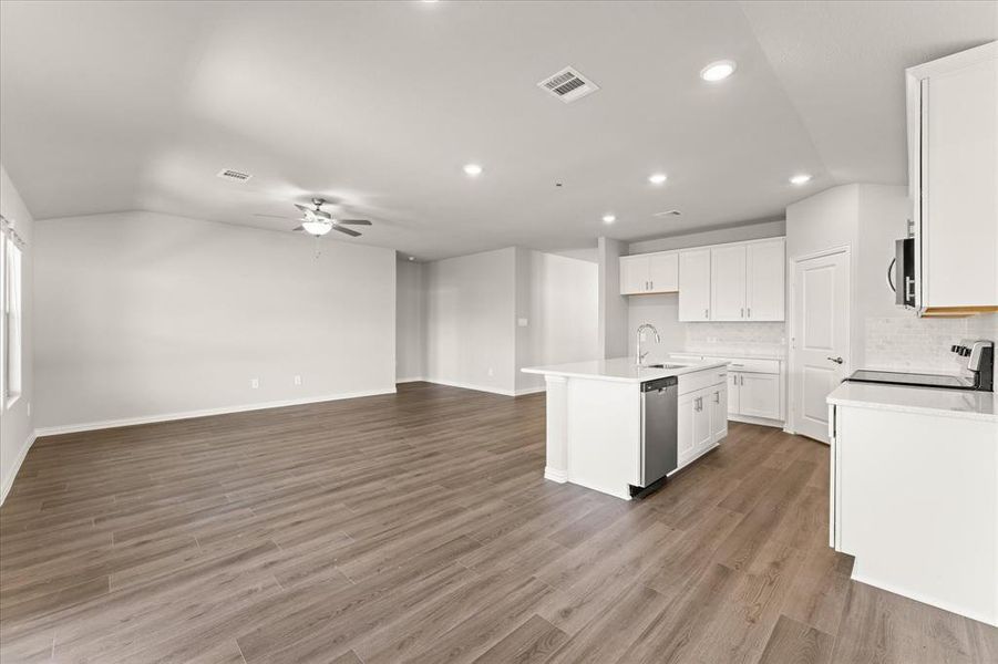 Kitchen with ceiling fan, a center island with sink, white cabinetry, and light hardwood / wood-style flooring