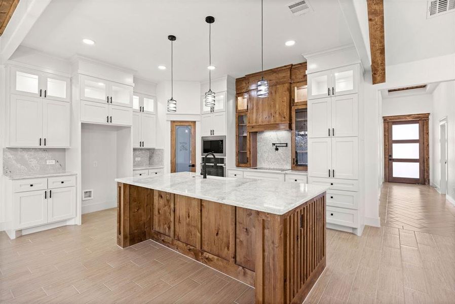 Kitchen with appliances with stainless steel finishes, a spacious island, visible vents, and white cabinetry