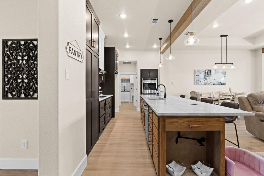 Kitchen featuring open floor plan, appliances with stainless steel finishes, a breakfast bar area, light wood-style flooring, and recessed lighting Kitchen featuring open floor plan, appliances with stainless steel finishes, a breakfast bar area, light wood-style flooring, and recessed lighting