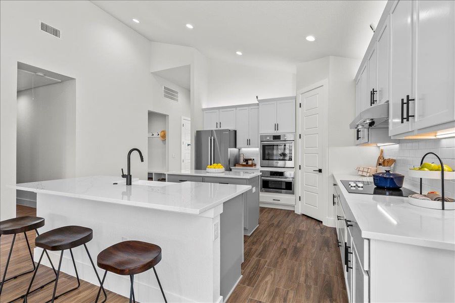 Kitchen with light stone countertops, tasteful backsplash, dark wood-style floors, stainless steel appliances, and a breakfast bar area