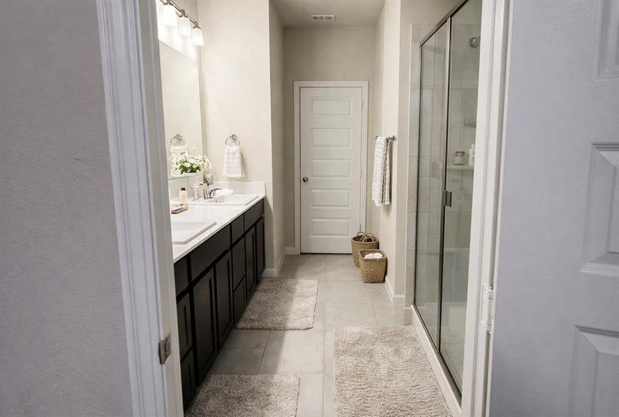 Full bathroom with double vanity, a stall shower, and light tile patterned flooring