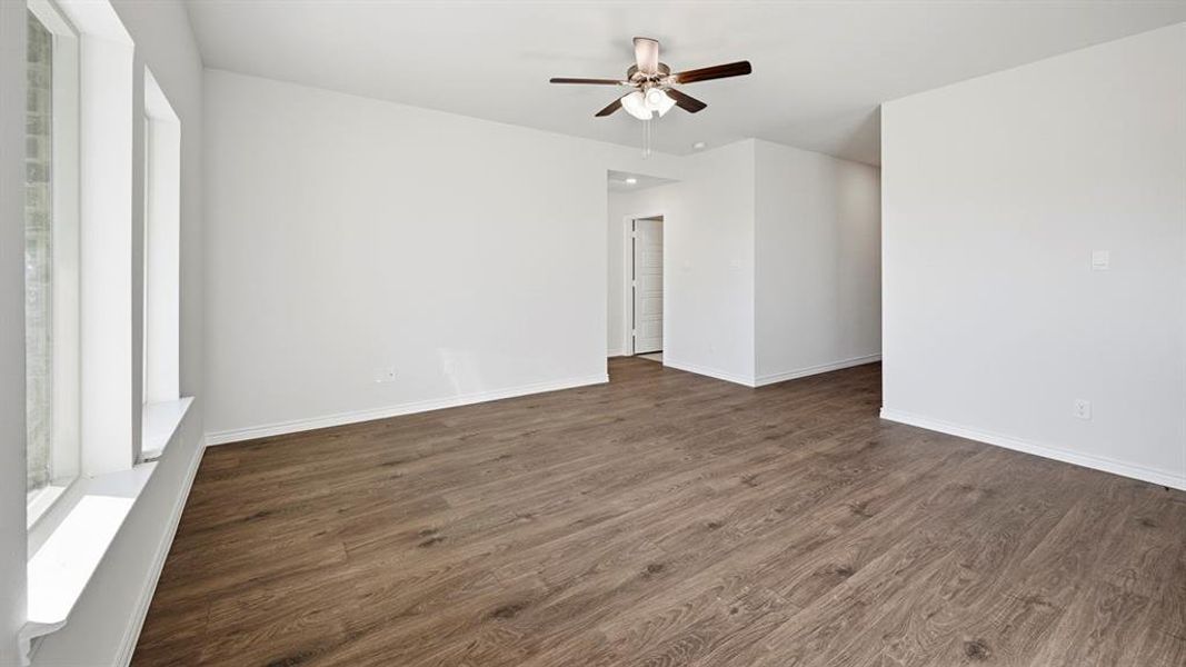 Spacious room featuring wood-look flooring, white walls, and a ceiling fan