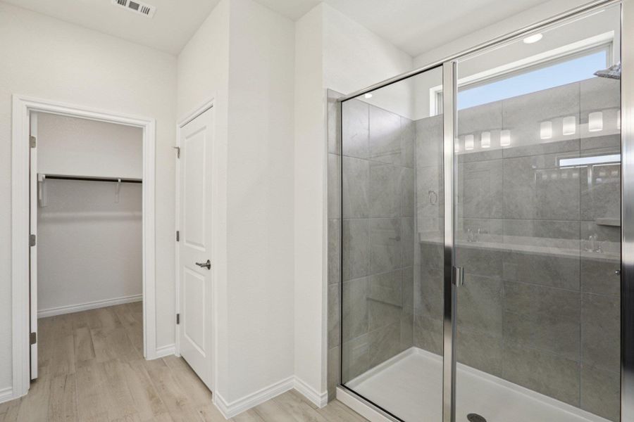 Full bath with a stall shower, light wood-style flooring, and a walk in closet