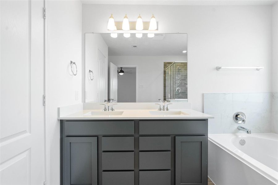 This primary bathroom is definitely move-in ready! Featuring dual sinks, stained cabinets with light countertops, mirror, high ceilings, neutral paint, sleek fixtures, and modern finishes.