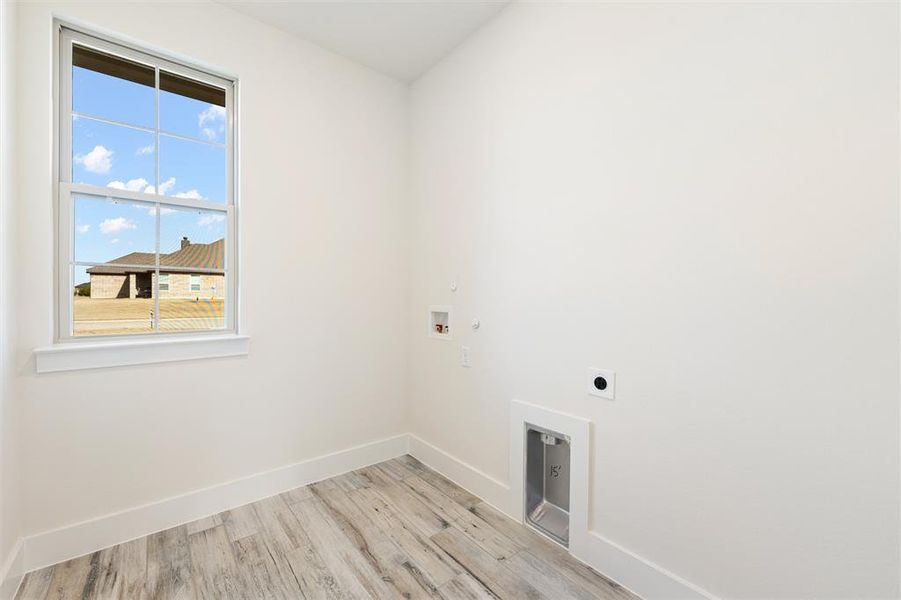 Laundry area with light wood-style flooring, gas dryer hookup, hookup for a washing machine, and hookup for an electric dryer