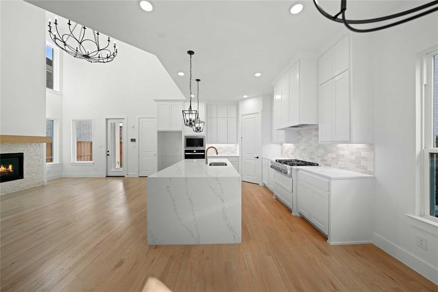 Kitchen featuring light stone counters, white cabinets, backsplash, light wood finished floors, and recessed lighting Kitchen featuring light stone counters, white cabinets, backsplash, light wood finished floors, and recessed lighting