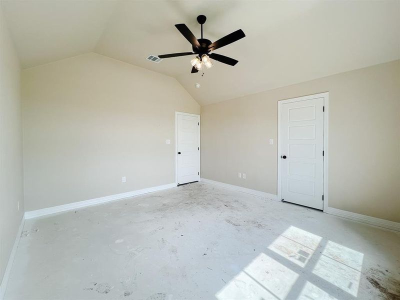Unfurnished bedroom with unfinished concrete floors, lofted ceiling, and a ceiling fan Unfurnished bedroom with unfinished concrete floors, lofted ceiling, and a ceiling fan
