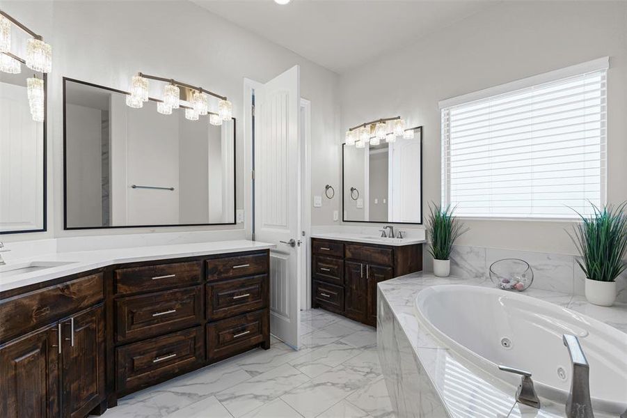 Primary Bathroom with two vanities, a tub with jets, and light marble finish flooring Primary Bathroom with two vanities, a tub with jets, and light marble finish flooring