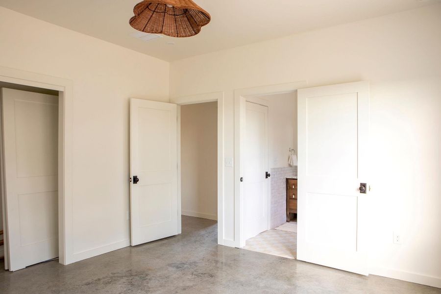 Unfurnished bedroom with finished concrete flooring and baseboards Unfurnished bedroom with finished concrete flooring and baseboards