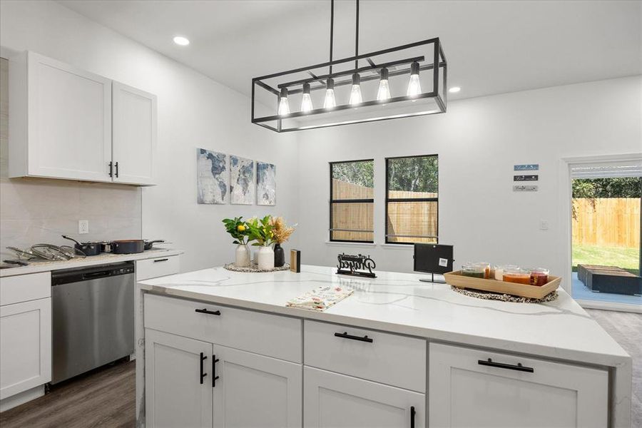 Kitchen featuring hanging light fixtures, dishwasher, a wealth of natural light, decorative backsplash, and white cabinets