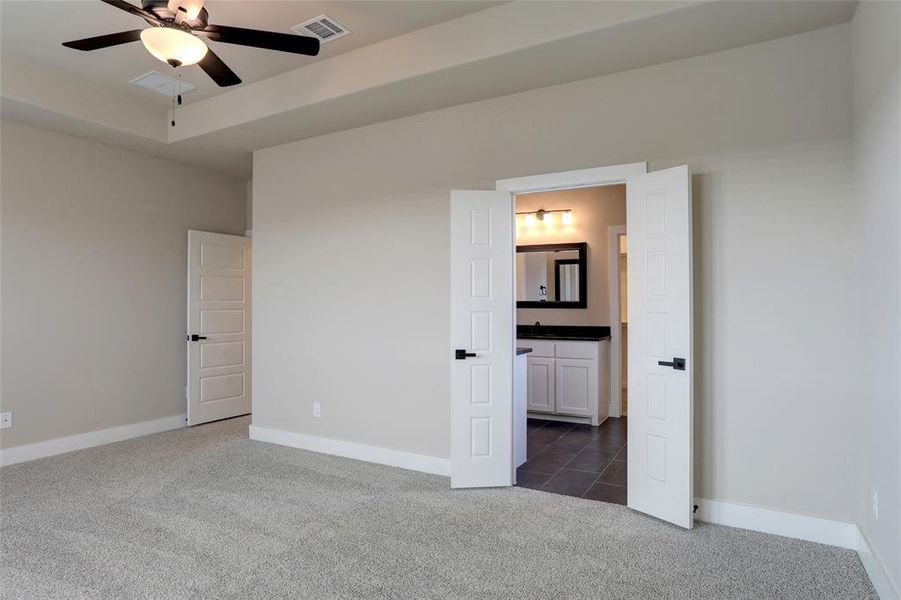 Unfurnished bedroom featuring connected bathroom and dark carpet