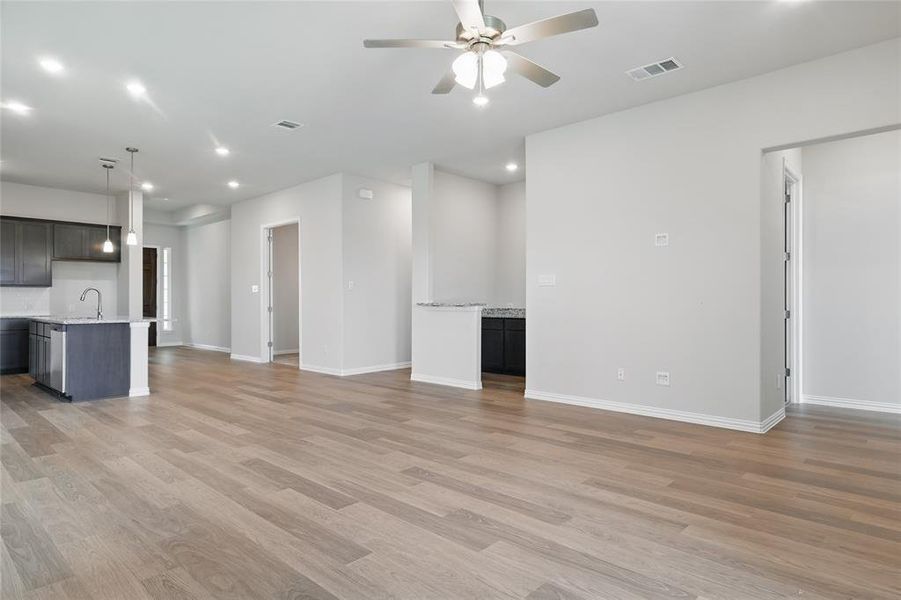 Unfurnished living room featuring ceiling fan, light wood-type flooring, a sink, baseboards, and recessed lighting Unfurnished living room featuring ceiling fan, light wood-type flooring, a sink, baseboards, and recessed lighting