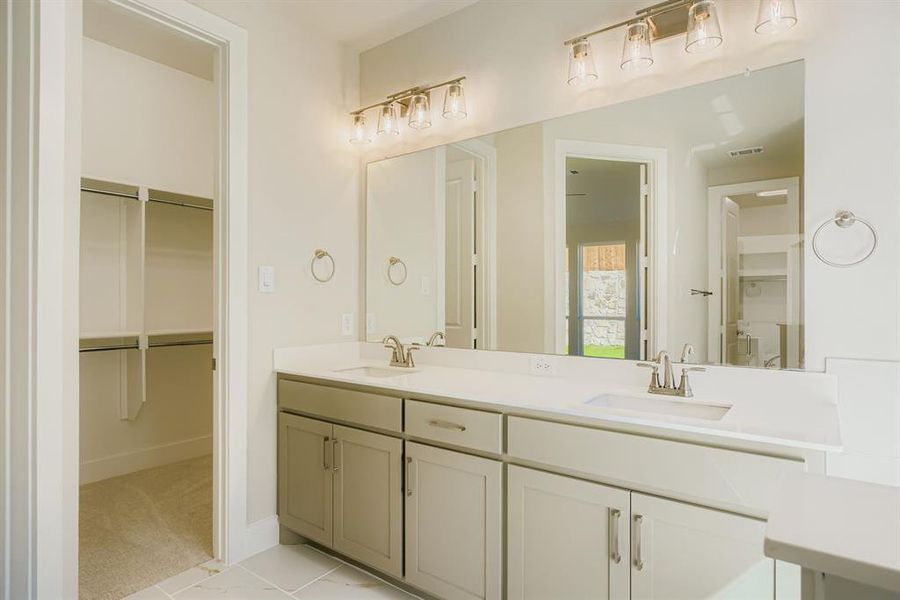 Full bathroom featuring a spacious closet, double vanity, light colored carpet, and light tile patterned flooring