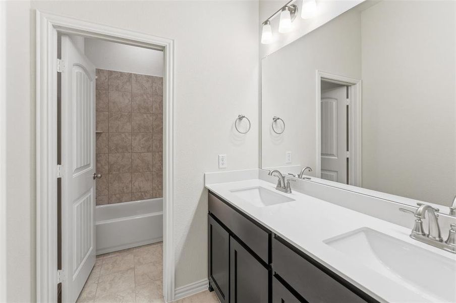 Bathroom with double vanity and bathtub / shower combination