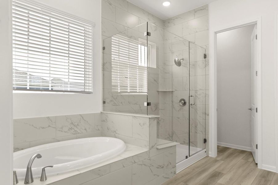 Bathroom with a marble finish shower, a garden tub, and wood finished floors