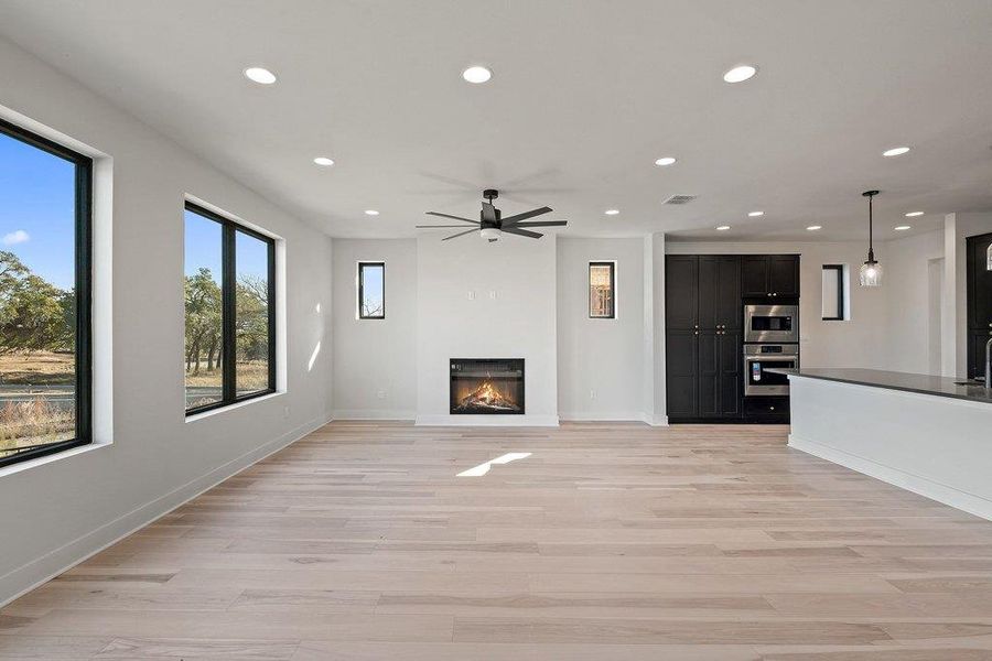 Unfurnished living room with recessed lighting, a glass covered fireplace, light wood-style flooring, and ceiling fan