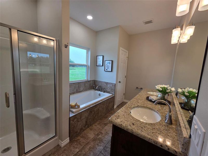 Full bath featuring double vanity, a garden tub, and a stall shower Full bath featuring double vanity, a garden tub, and a stall shower