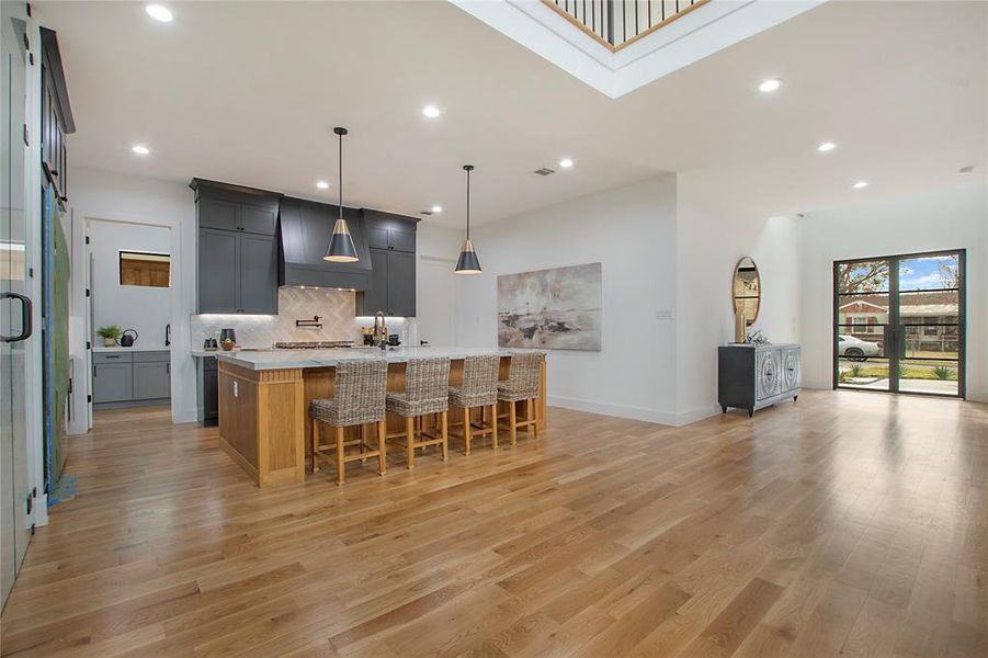 Kitchen featuring a large island with sink, light hardwood / wood-style flooring, pendant lighting, and a kitchen breakfast bar