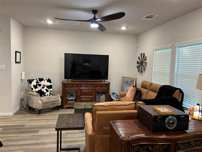 Spacious living area featuring wood-finish flooring, recessed lighting, and a dark wood ceiling fan