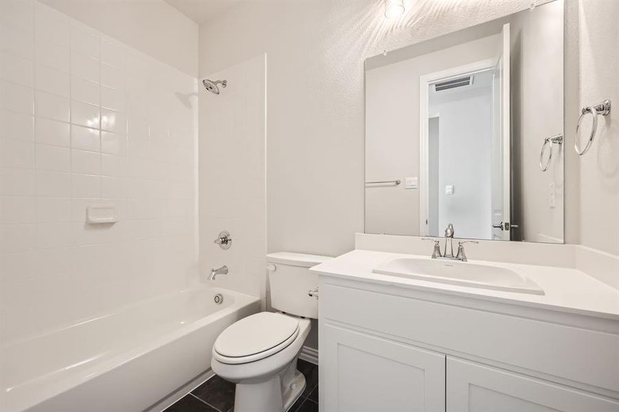 Full bathroom with vanity, tiled shower / bath combo, toilet, and tile patterned flooring