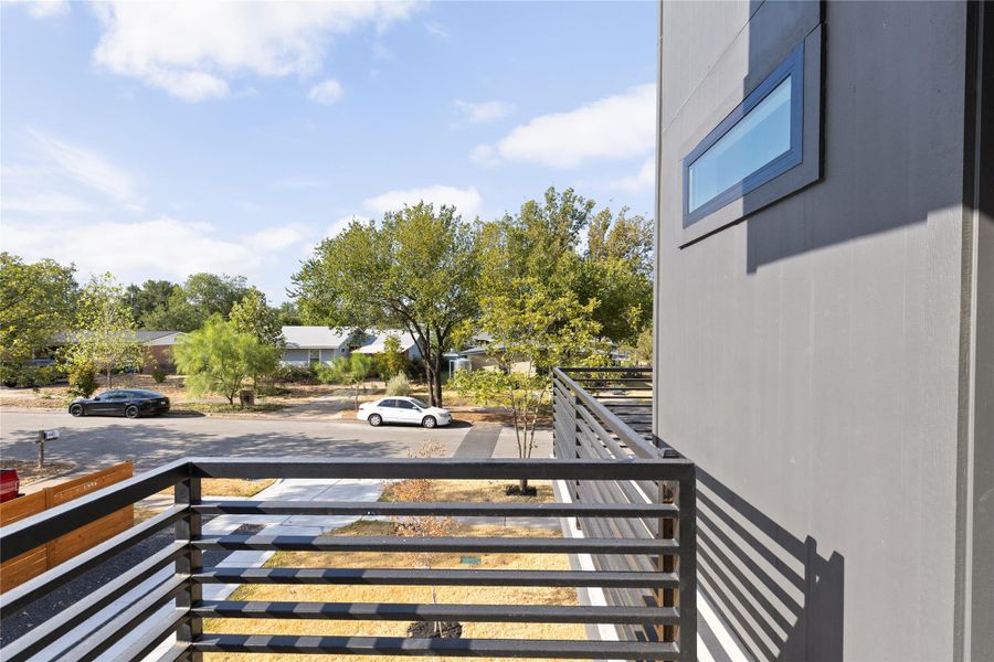 An elevated perspective overlooks the surrounding neighborhood from a modern balcony with horizontal metal railings.