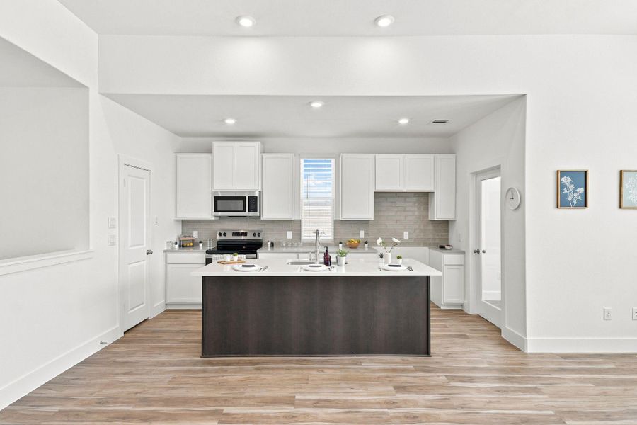 Modern kitchen featuring a large island with quartz countertop, stainless steel appliances, and abundant cabinetry. Modern kitchen featuring a large island with quartz countertop, stainless steel appliances, and abundant cabinetry.