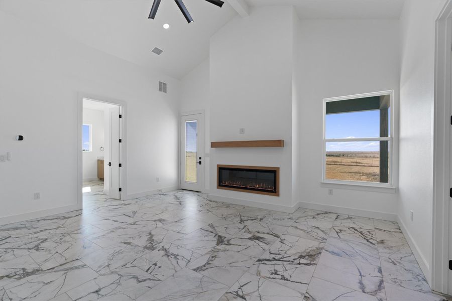 A spacious primary bedroom with soaring vaulted ceilings and elegant tile flooring. A spacious primary bedroom with soaring vaulted ceilings and elegant tile flooring.