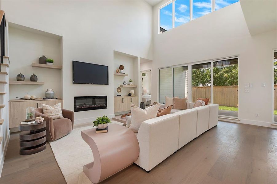 Living room with built in shelves, hardwood / wood-style flooring, and a towering ceiling