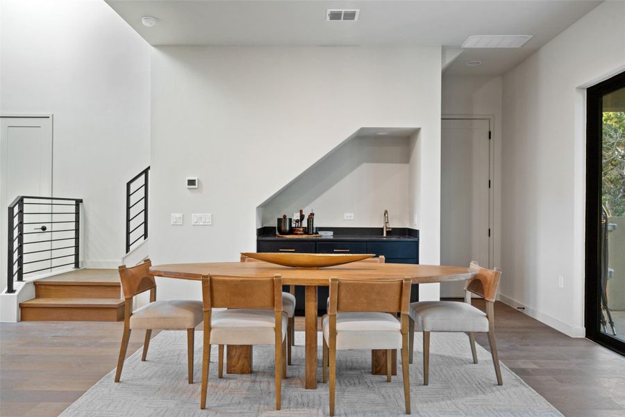 A stylish dining area offers convenient access to a wet bar and modern staircase.