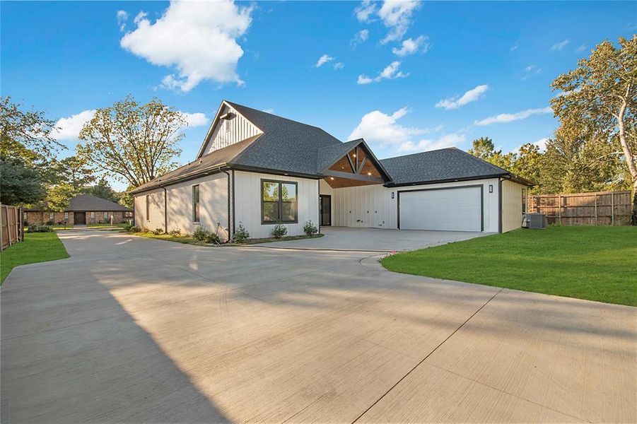 View of front of property with driveway, a shingled roof, and an attached garage