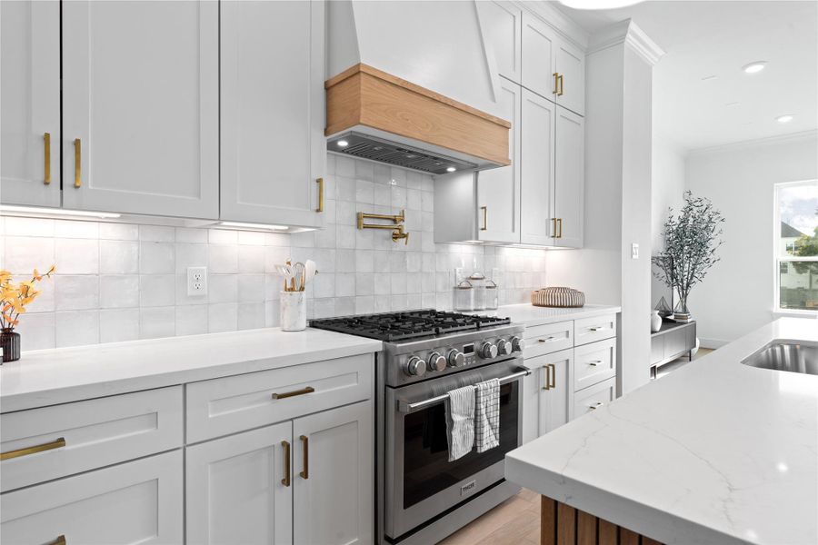 This gourmet kitchen is equipped with a premium Thor 6-burner gas range, complemented by a sleek pot filler and custom wood-accented vent hood - blending luxury, functionality, and timeless design.