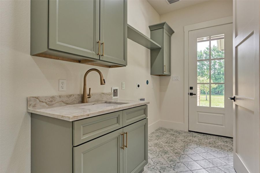Spacious laundry room with sage green cabinetry, a deep utility sink, and direct exterior access — function meets farmhouse charm. Spacious laundry room with sage green cabinetry, a deep utility sink, and direct exterior access — function meets farmhouse charm.