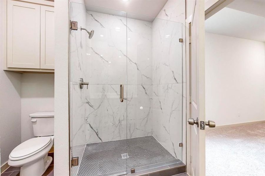 Bathroom featuring toilet and a shower with shower door