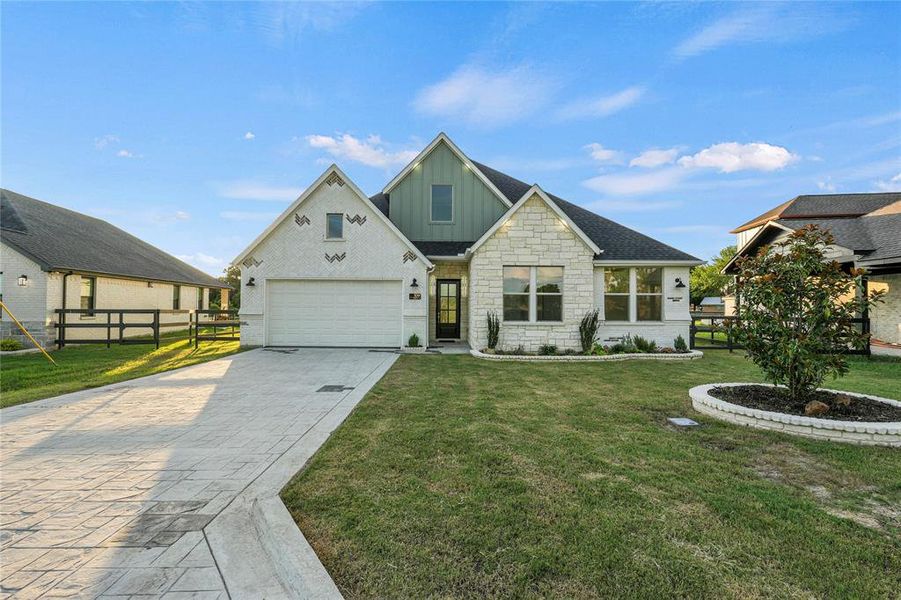 View of front of property featuring board and batten siding, decorative driveway, and stone siding View of front of property featuring board and batten siding, decorative driveway, and stone siding